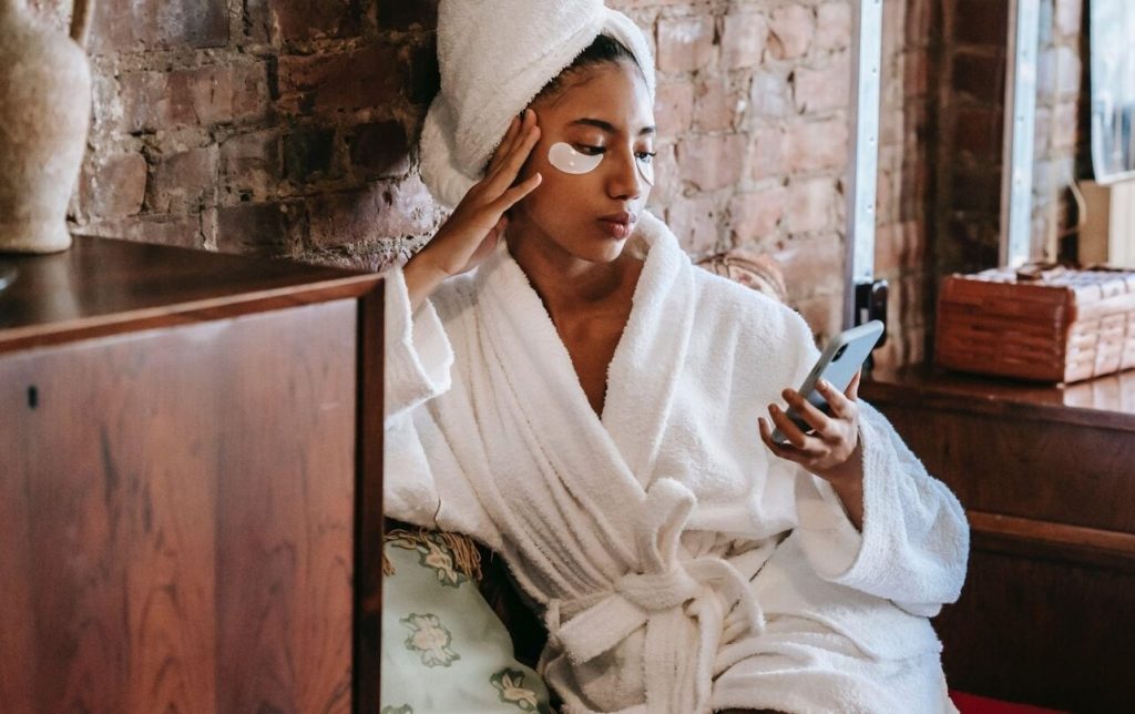 Young woman with her hair up in a towel and eye patches at a salon