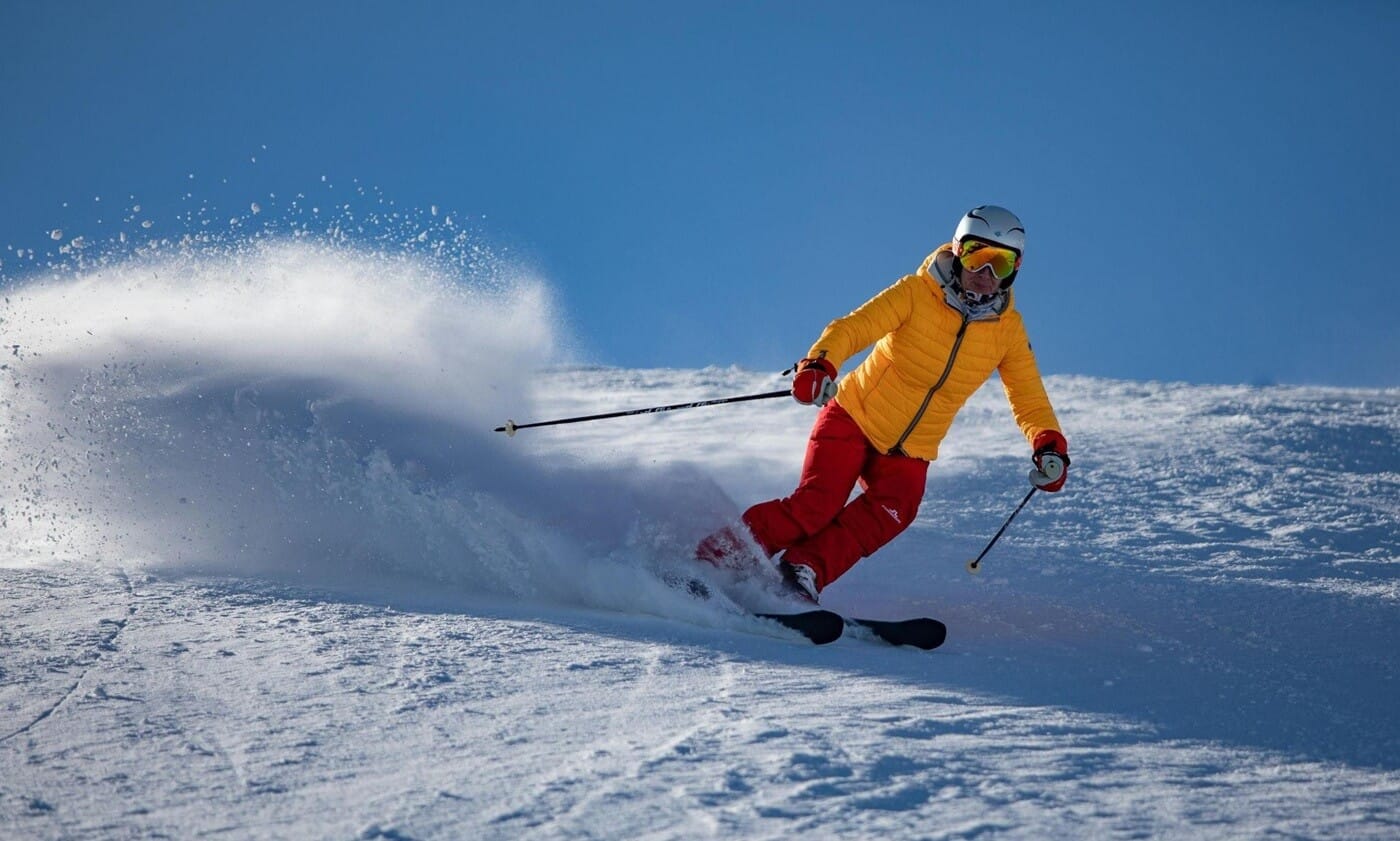Person in a yellow jacket and red pants skiing downhill