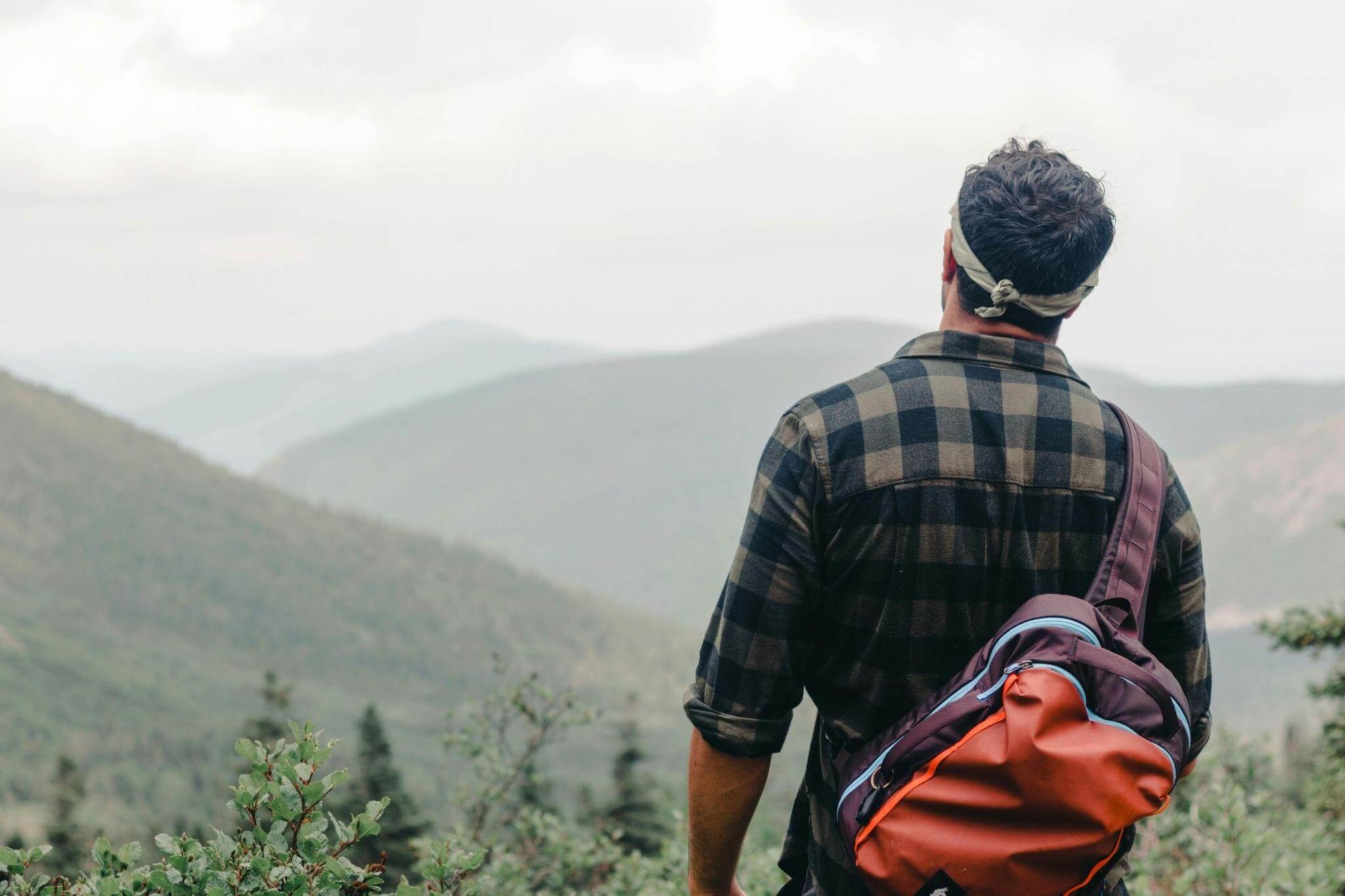 Hiker with a backpack, looking at mountains in the distance